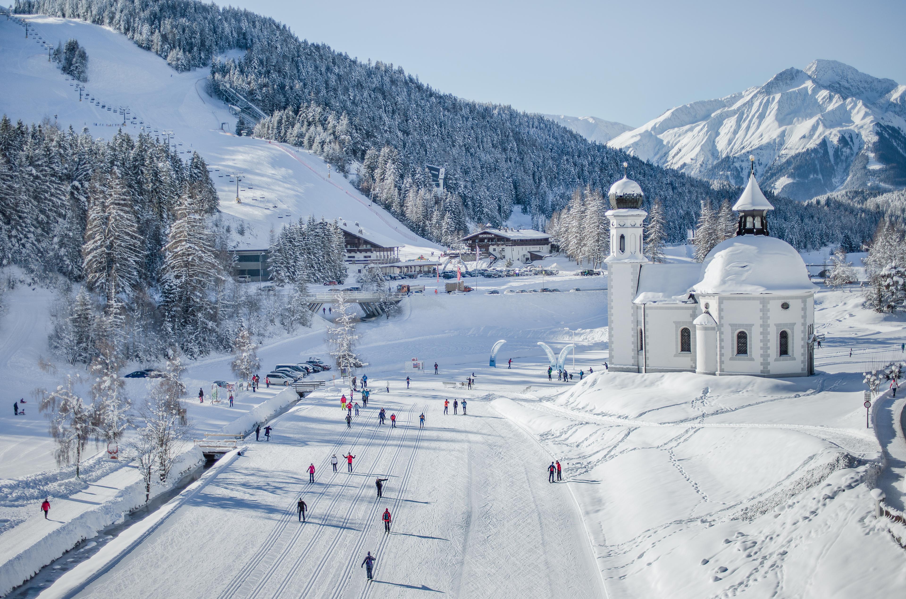 Skiiers skiing past traditional church in Seefeld ski resort